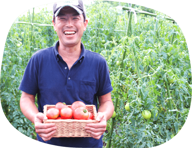 笑顔の苅部さんと収穫したトマト